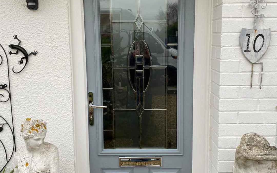 Door installation team standing with a wooden front door featuring decorative glass panels